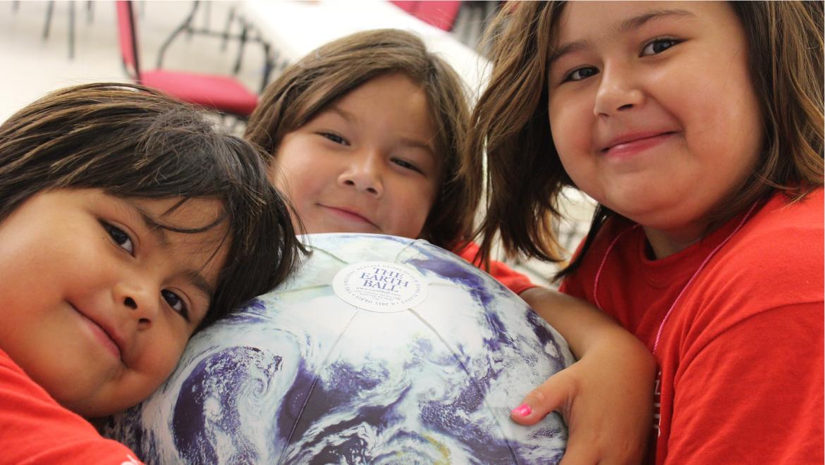 Youth program participants holding an Earth shaped ball.