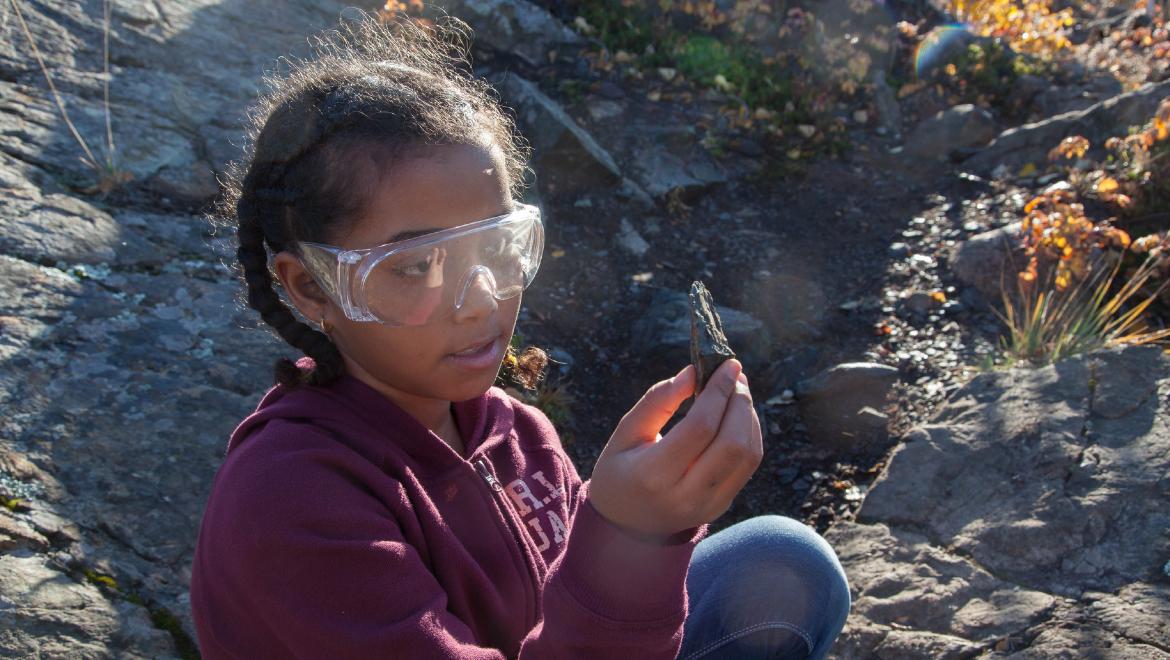 Élève examinant une roche en plein air.