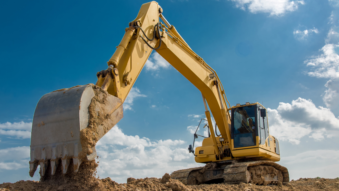 Large yellow hydraulic excavator using its bucket to sctiocoop and lift soil at a construn or mining site under a blue sky. • Grande excavatrice hydraulique jaune utilisant son godet pour creuser et soulever de la terre sur un site de construction ou minier, sous un ciel bleu.