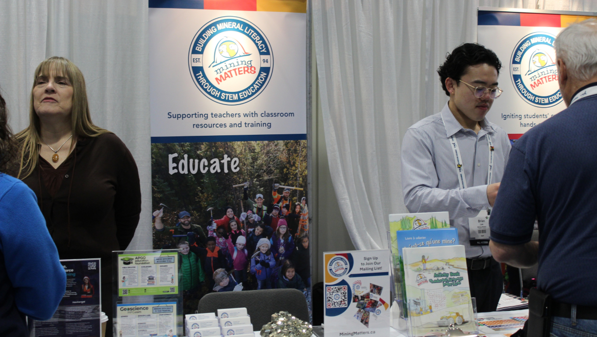 Mining Matters' booth with rock and mineral samples and educational pamphlets along with staff engaging with visitors at the event.