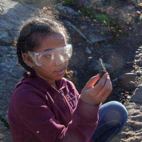 Élève examinant une roche en plein air.