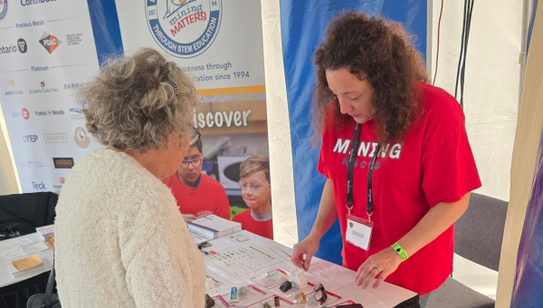 Mining Matters staff showcasing rocks and minerals sample to the public • Une mine de renseignements présente des échantillons de roches et de minéraux aux membres du public.